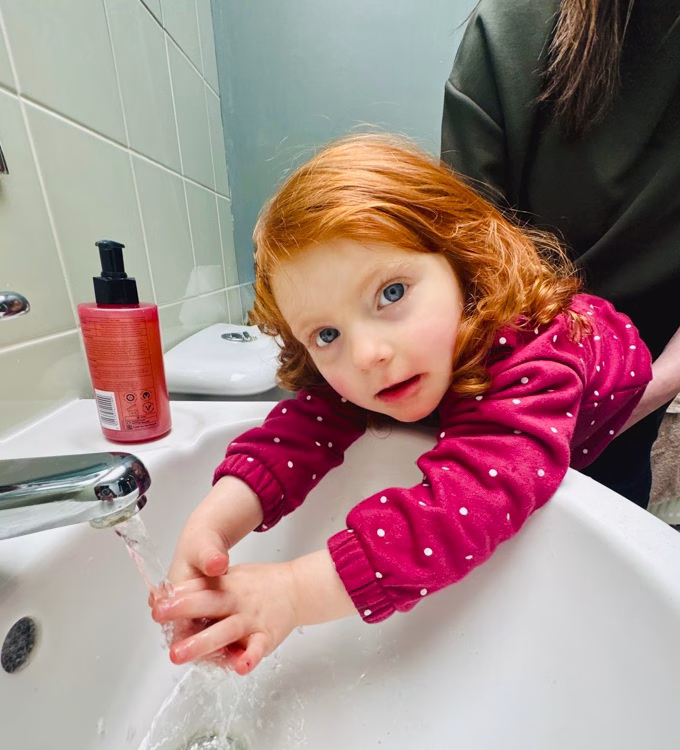Little girl washing hands in a sink